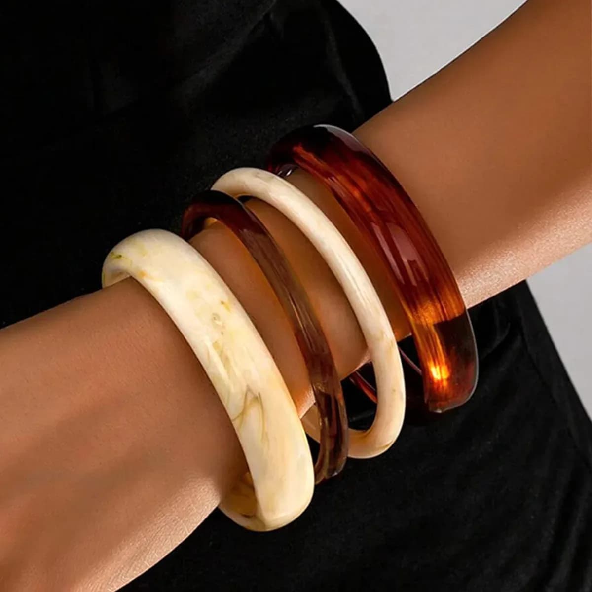 Chunky resin bangles worn stacked together on a woman's wrist