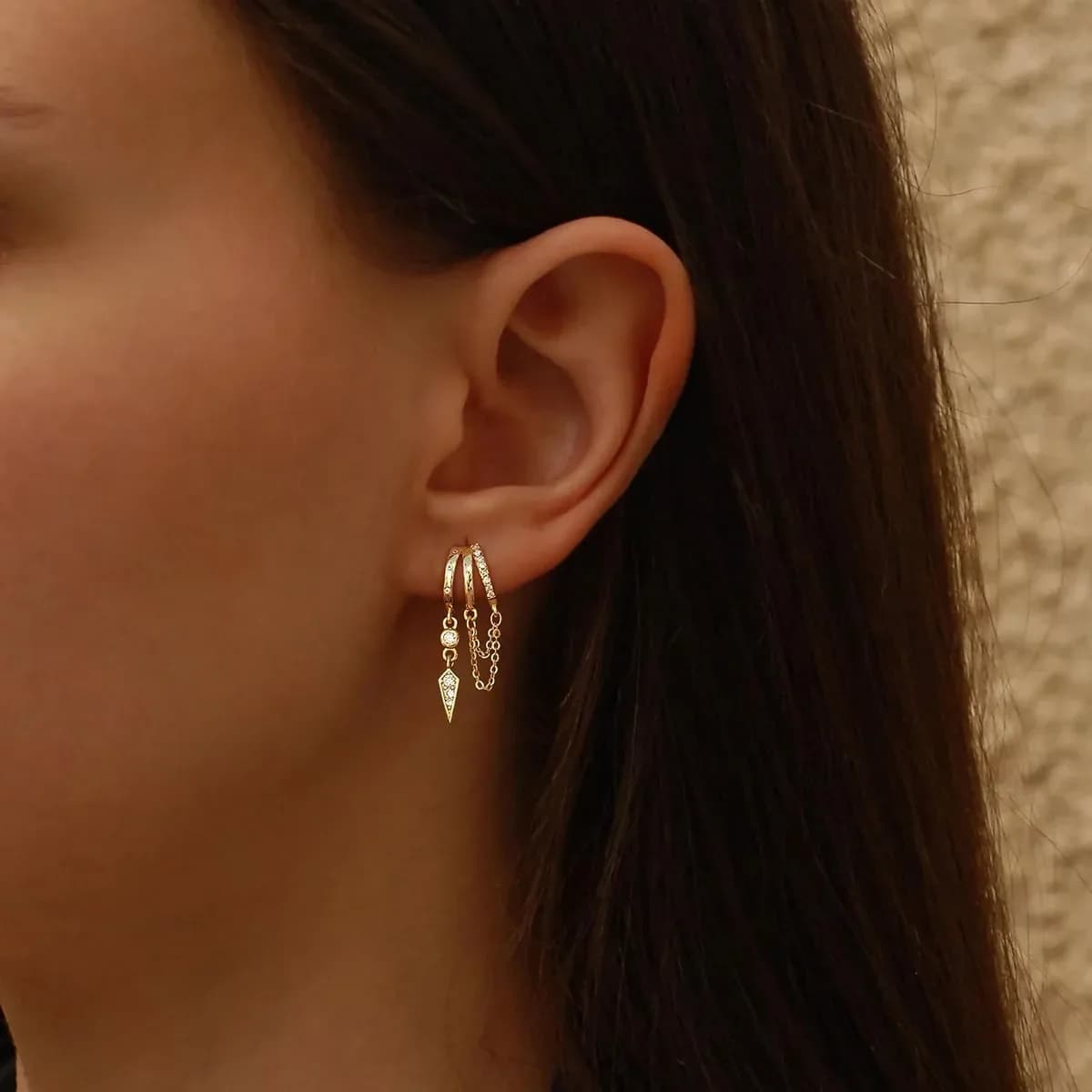 Model wearing gold dangle huggie earrings, front portrait shot