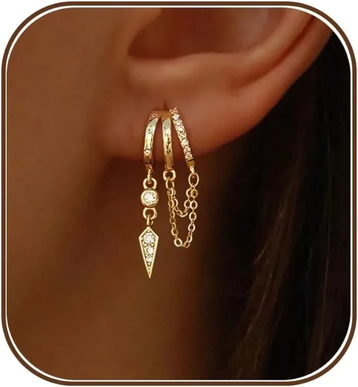 Gold dangle huggie earrings worn on the ear, close view