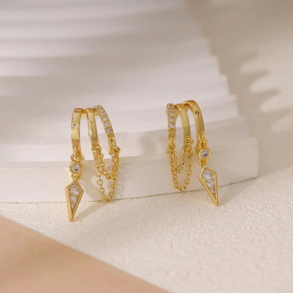 Pair of gold dangle huggie earrings side by side