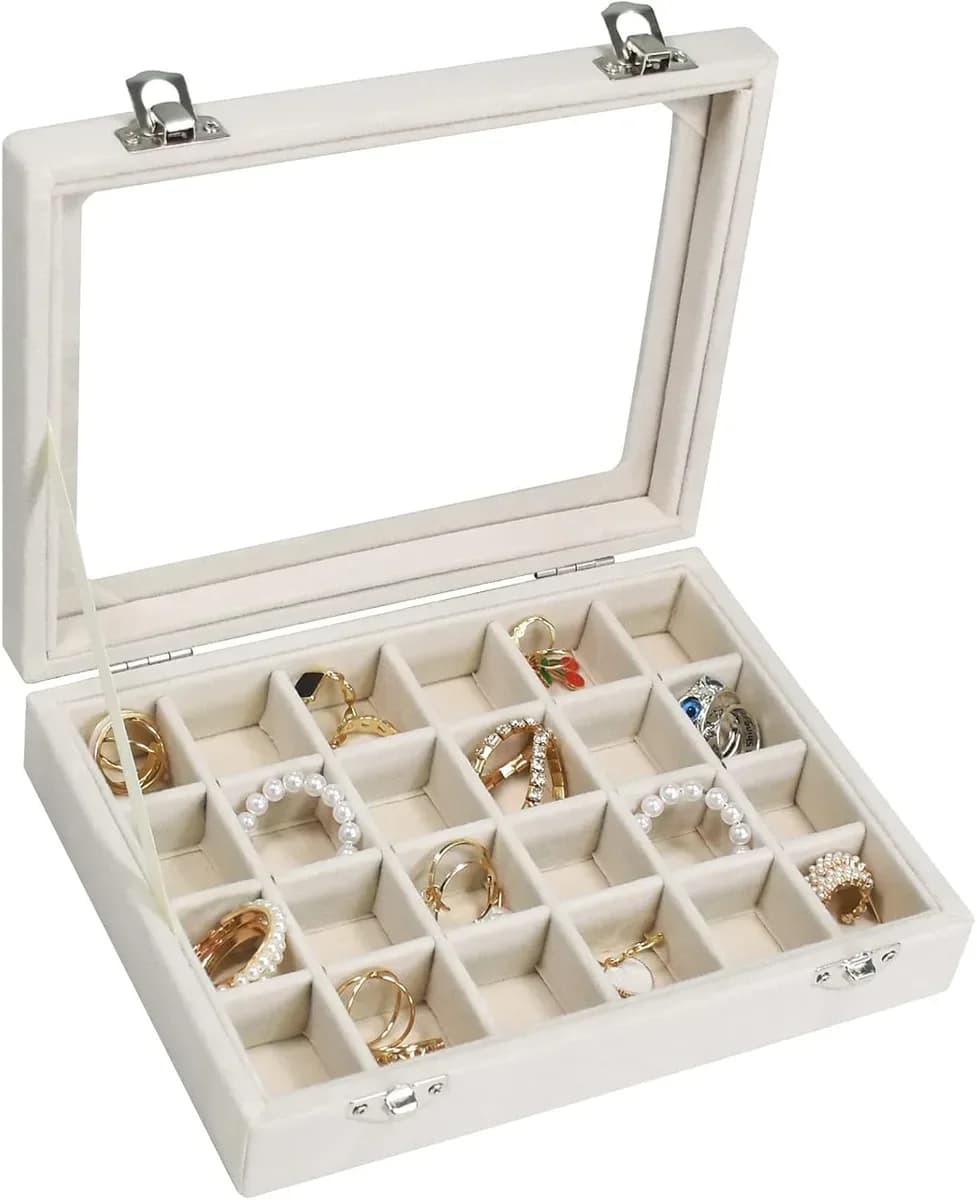 Beige velvet jewelry box with glass lid filled with rings